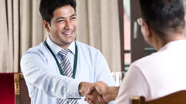 Two people shaking hands in an office setting.