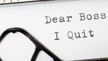 Typed words on paper saying 'Dear Boss, I Quit' with typewriter keys visible.