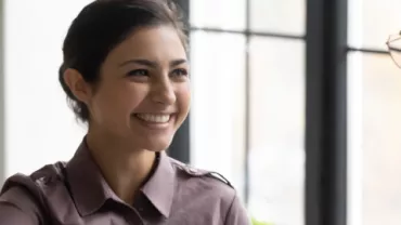 Person smiling while shaking hands in an office setting.