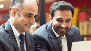 Two Indian men in business suits looking at one laptop screen