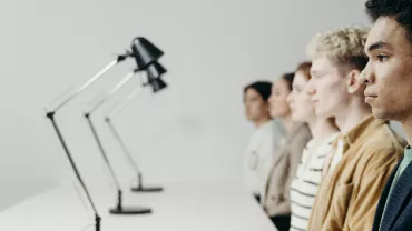 Row of people in profile view behind modern desk lamps.