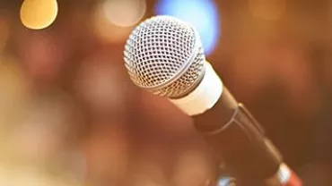 Close-up of a microphone in a warm, blurred background setting.