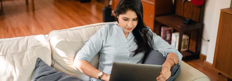 Person sitting on a couch using a laptop.