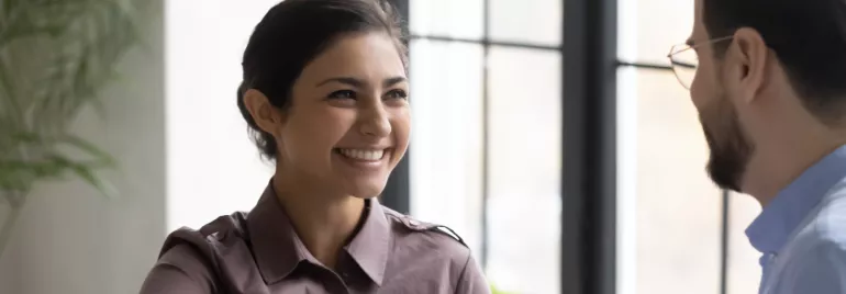 Person smiling while shaking hands in an office setting.