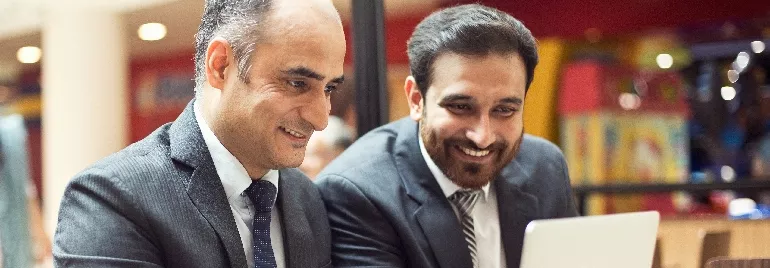 Two Indian men in business suits looking at one laptop screen